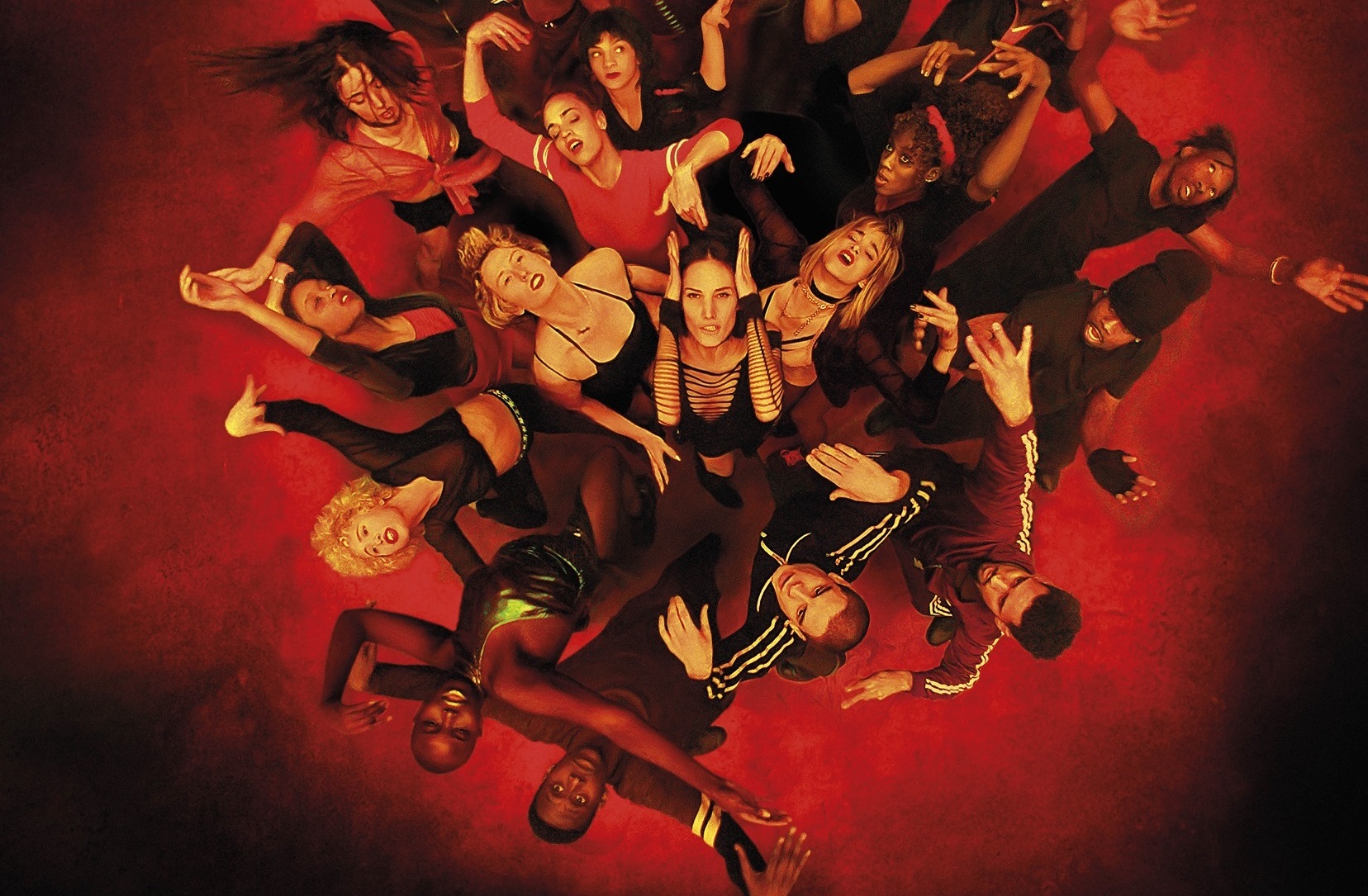 Zdjęcie; widok z góry na grupę ludzi w czarnych strojach wygiętych w tańcu