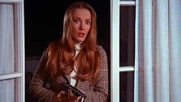 Zdjęcie; Zaskoczona kobieta stoi w drzwiach z pistoletem w ręku